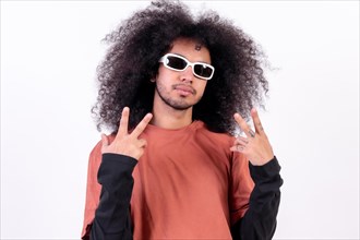 Portrait wearing sunglasses and doing the victory symbol. Young man with afro hair on white background
