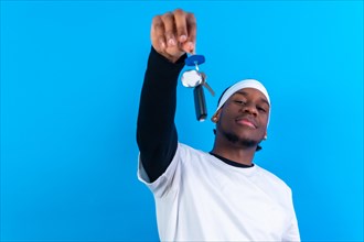 Black ethnic man in white clothes on a blue background happy with the new house keys