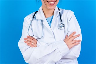 Portrait of smiling female doctor in medical gown standing isolated on blue