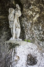 Weathered medieval sculpture of Saint Christopher and Jesus in the church of the fortified troglodyte town La Roque Saint-Christophe