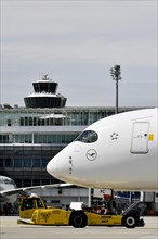 Lufthansa Airbus A350-900 towing with push-back truck in front of Terminal 2 with tower