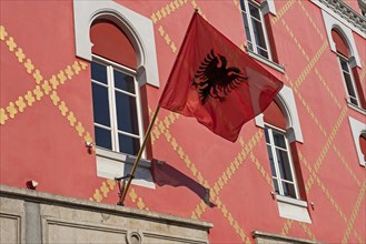 Red flag of Albania with silhouetted black double-headed eagle on facade in Tirana