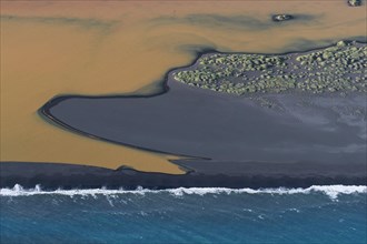 Aerial view over Landeyjarsandur showing beach with black volcanic sand and brown water laden with sediment flowing in sea in summer