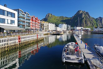 Modern houses reflected in the calm waters of the small harbour of Svolvaer