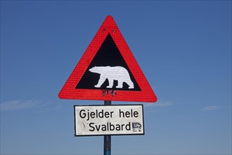 Polar bear warning sign against blue sky