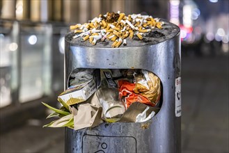 Full waste bins with packaging waste and cigarette butts