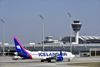 Iceland Air aircraft Boeing B737 MAX taxiing with Terminal 1 and Tower