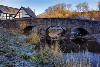 The old Hoennetal bridge in autumn with half-timbered house in Volkringhausen