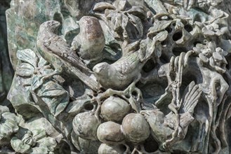 Close up of old Chinese statue showing sculpted birds made of jade