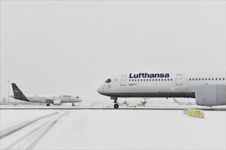 Aircraft taxiing on taxiway in winter snow flurry for de-icing and take-off clearance