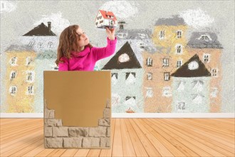 Child in a box with a model of a house
