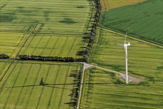 Aerial view over farmland with wind turbine amidst agricultural parcels