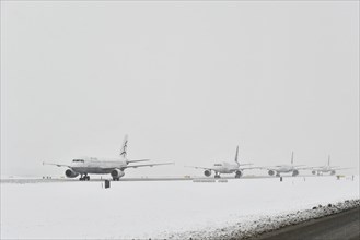 Aircraft taxiing on taxiway in winter snow flurry for take-off clearance