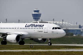 Lufthansa Airbus A320-200 taxiing on runway north with tower in the background