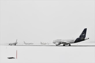 Aircraft in wait in winter snow flurry for de-icing and take-off clearance