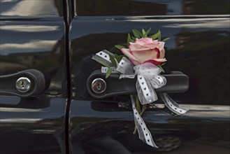 Roses and bows decoration on car handle from wedding car