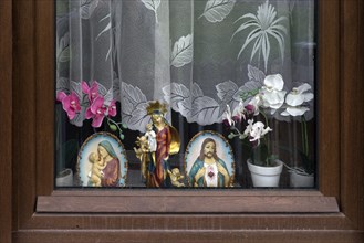 Figure of a saint and holy images in a window under the curtains