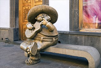 Bronze sculpture of Mariachi sitting on bench by sculptor Rodo Padilla in Calle Independencia at Tlaquepaque