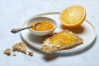Orange marmalade in small bowls and on crispbread