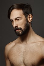 Portrait of topless serious man with beard and mustache looking tired