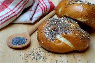 Buns with poppy seeds, linseeds and sesame seeds, pretzel roll with blue poppy seeds in cooking spoon