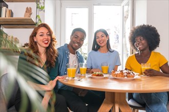 Portrait of multi-ethnic friends having a breakfast with orange juice and muffins at home