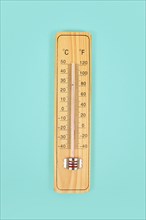 Wooden thermometer on green background