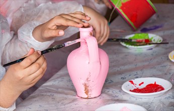 Young children decorating their handmade clay pottery