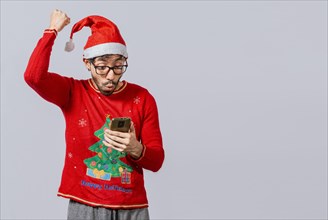 People in santa hat looking at cell phone excited, Excited young man in christmas hat using cellphone celebrating, Excited guy in christmas hat looking at cellphone and celebrating