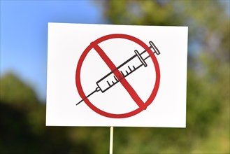 Anti vaccine demonstration sign with syringe drawing in red crossed out circle