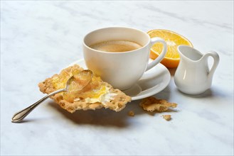 Orange marmalade in small bowls and on crispbread and cup of coffee