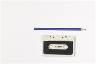 Old compact cassette with pencil on white background, copy room
