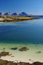 Crystal clear water in a shallow bay, sandy beach, view of the coastal mountains of the Seven Sisters, Helgeland coasts, Sandnessjoen, Nordland, Norway, Europe