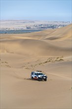 Off-road vehicle in sand dunes above the Orange River, also Oranjemund, Sperrgebiet National Park, also Tsau ÇKhaeb National Park, Namibia, Africa