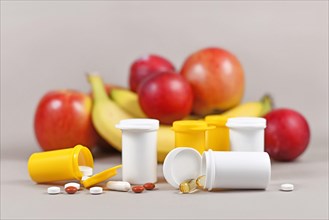 Food nutrition supplement capsules and pills with with plastic bottles in front of fruits