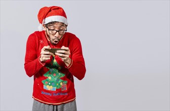 Amazed man looking at a christmas offer online, Guy looking at a christmas promo on phone. Online christmas special offers concept, Surprised people watching a christmas promotion on the phone