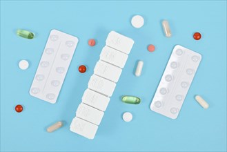 Pills, capsules, blister packs and pill box on blue background