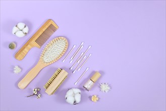 Eco friendly wooden beauty and hygiene products like comb and soap in corner of purple background with copy space