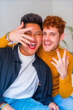 Portrait of beautiful gay couple putting on makeup, with painted nails indoors at home, lgbt concept
