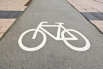 Cycle track with white bicycle symbol painted on ground on street in Germany