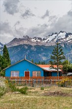 Blue wooden house, Cerro Castillo mountain range in the back, Villa Cerro Castillo village, Cerro Castillo National Park, Aysen, Patagonia, Chile, South America