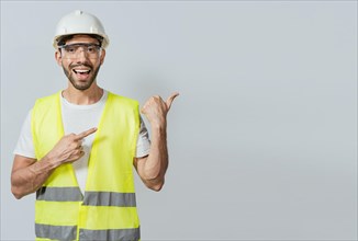 Construction engineer with vest pointing at an advertisement. Engineer man pointing to side. Builder engineer pointing finger to the right isolated, Portrait of engineer man pointing aside