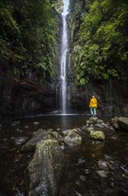 Young woman standing by the river and waterfall Cascata das 25 Fontes, long exposure, Rabacal, Paul da Serra, Madeira, Portugal, Europe
