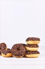 Chocolate glazed donuts with sprinkles on white wooden background with copy space