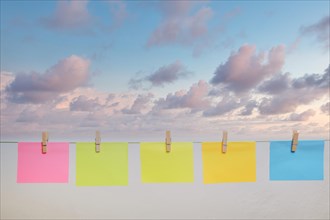 Colorful post it on a clothesline with cloudy sky in the background