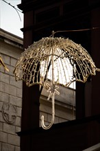 Beautiful umbrella of golden color hanging in the street for decorative purposes