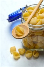 Conchiglie, shell pasta in glass container with cooking spoon, pasta