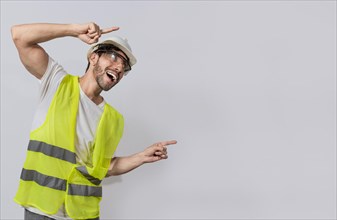 Builder engineer pointing finger to the right isolated, Construction engineer with vest pointing at an advertisement. Engineer man pointing to side. Smiling engineer man pointing aside
