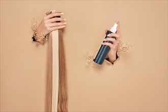 Hands with flowers hold strands of hair for extensions on a beige background. hair beauty