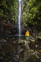 Young woman standing by the river and waterfall Cascata das 25 Fontes, long exposure, Rabacal, Paul da Serra, Madeira, Portugal, Europe